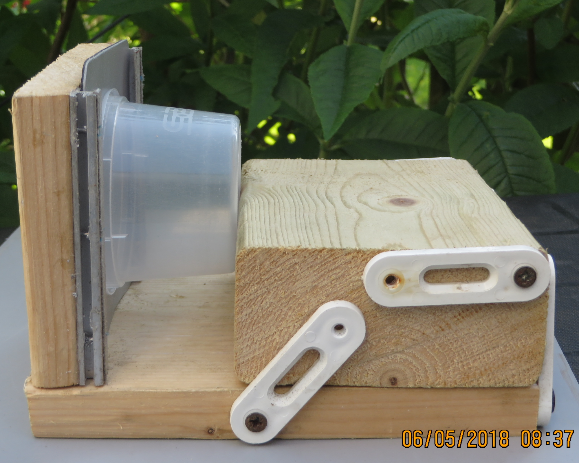 Block of wood on a hinged base to allow for wedging a pot between it to keep it vertical