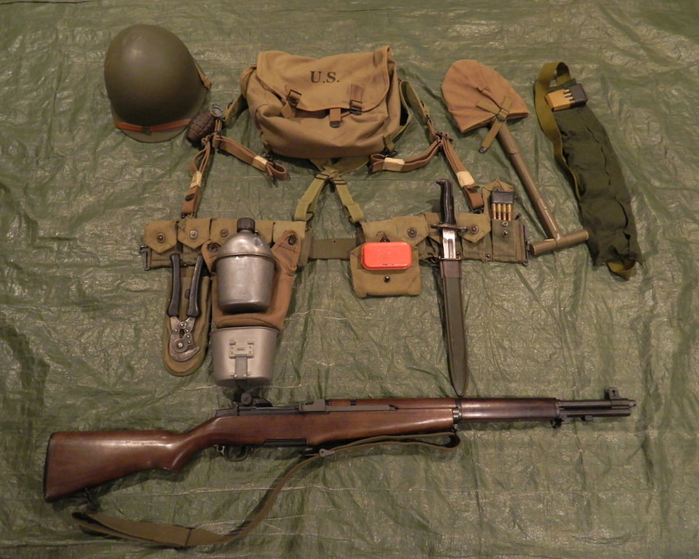 Layed out WW1 soldier equipment consisting of a pocket spade, helmet, utility belt satchel bag and rifle