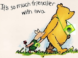 Classic Winnie the Pooh holding hands with Piglet, the words "It's so much friendler with two" above them. Cameras have been edited around their necks