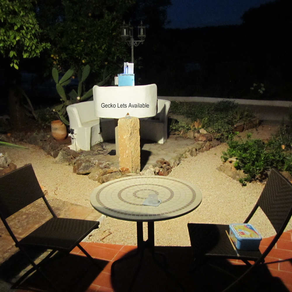 Garden patio in the evening, with a photoshop sign saying 'Gecko Lets Available'